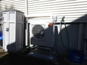 An outdoor condenser and heat pump installed outside a Brighton, MA, home. 