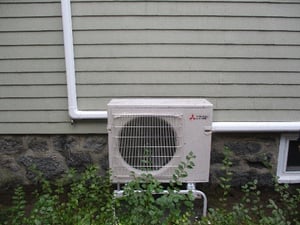Mitsubishi ductless mini split AC condenser installed outside West Roxbury colonial style home.