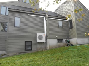 Outdoor condenser heat pump installed outside contemporary home in Gloucester, MA.